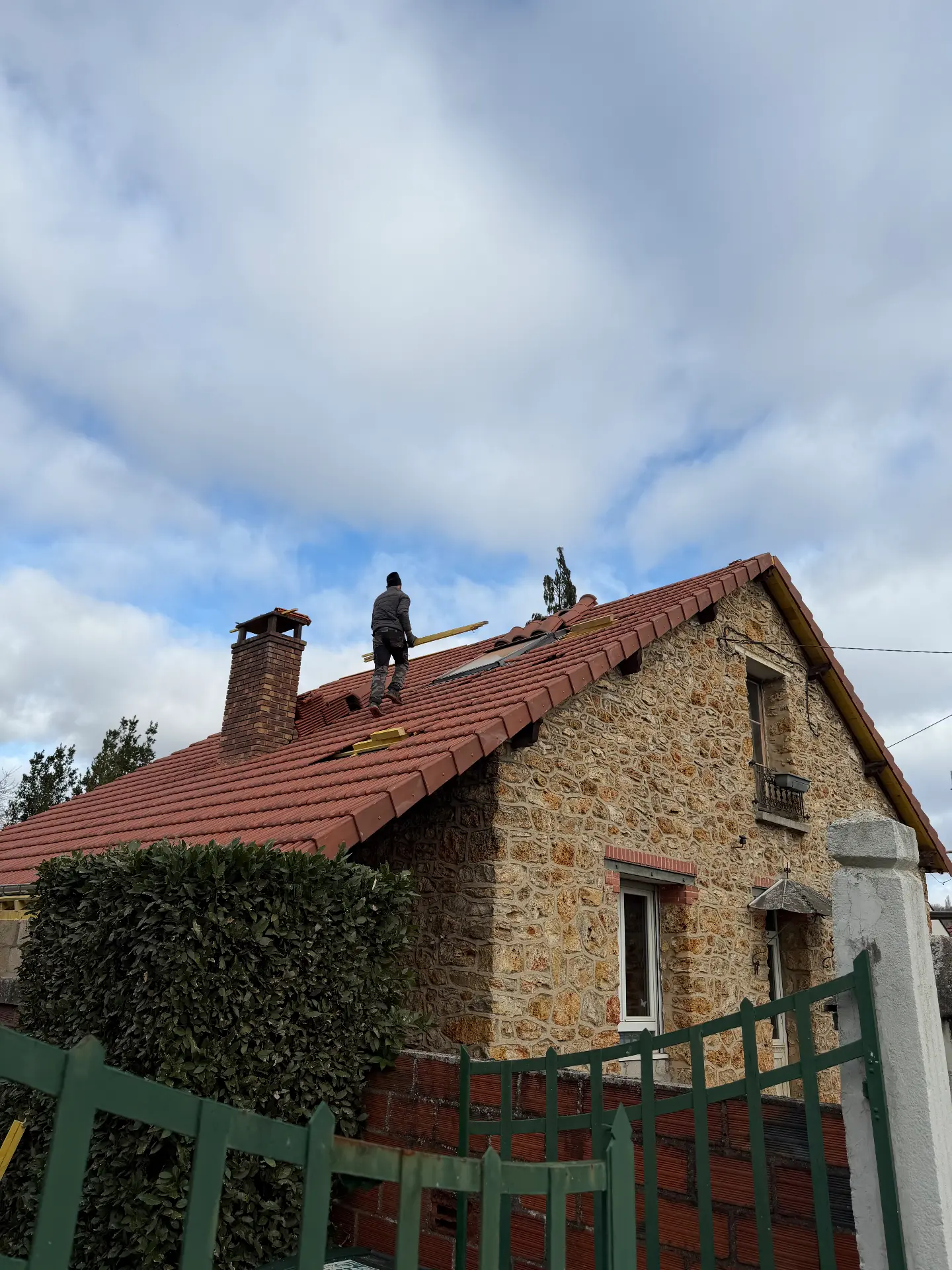 Couvreur sur une toiture en tuiles rouges
